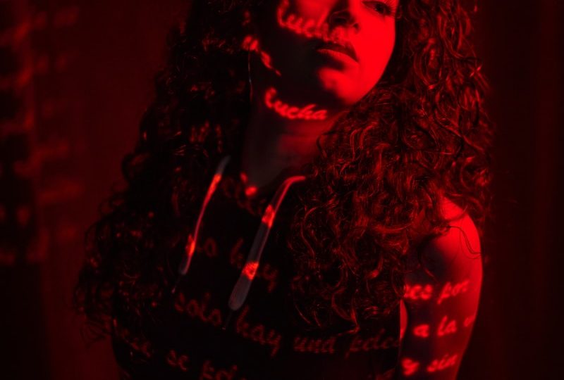 a woman with long curly hair standing in a dark room